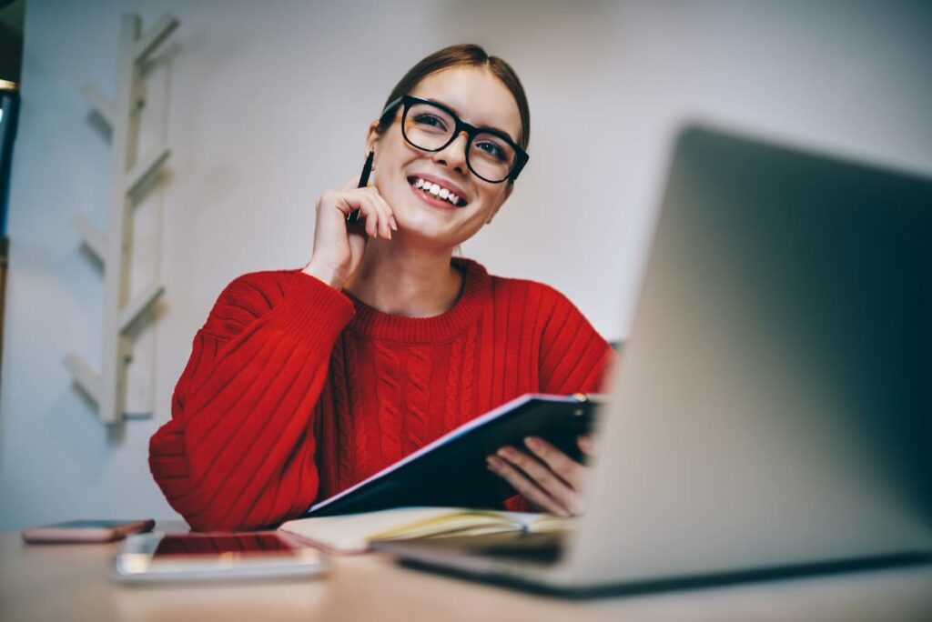 女性がノートパソコンの前で注文が入り楽しそうに笑顔で座っている
